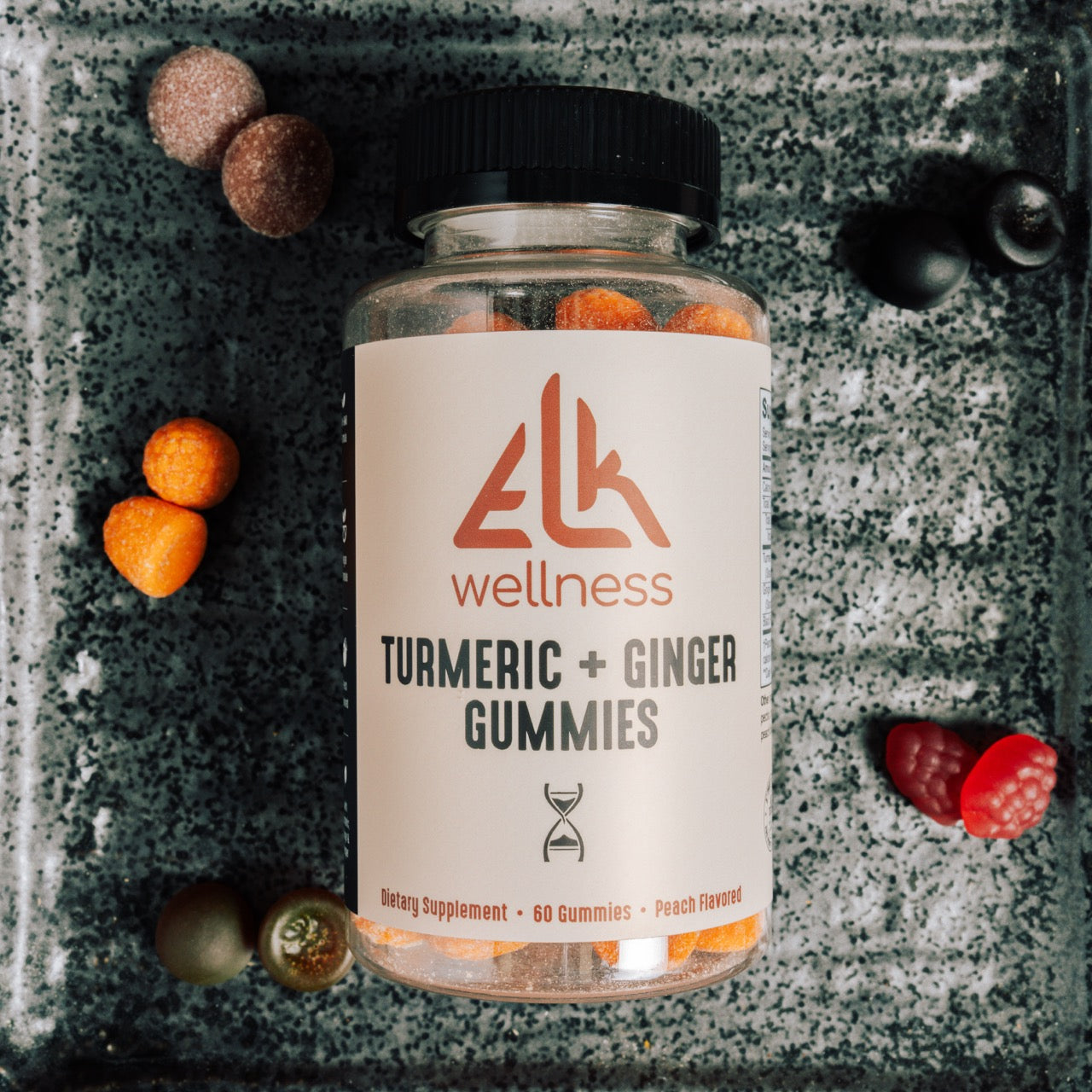Bottle of Elk Wellness Turmeric + Ginger Gummies on a textured surface with gummy bears around.