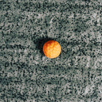 Single orange gummy on a textured gray surface